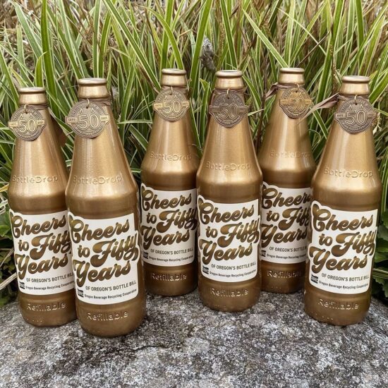 Six golden bottles for the OBRC 50th anniversary treasure hunt, photographed outdoors on a rock.