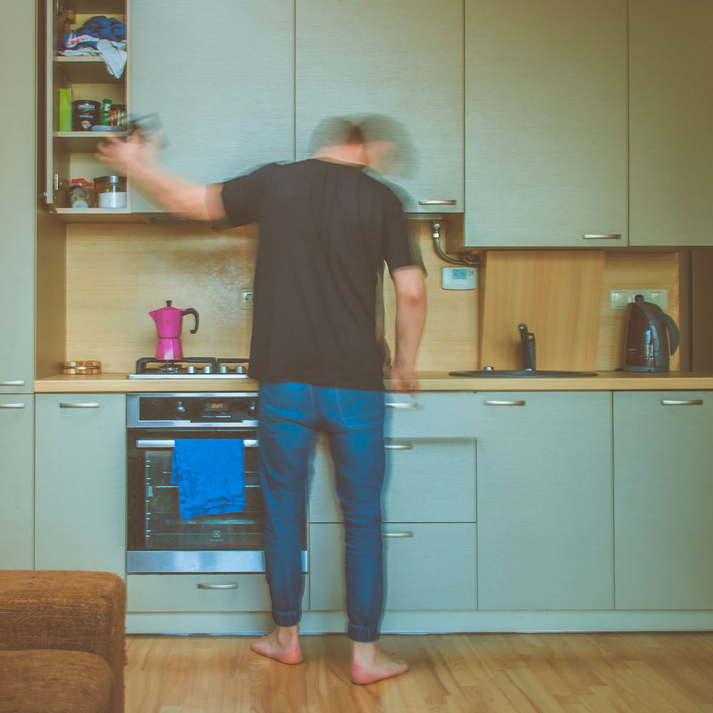 A man in a kitchen searching in vain for a utensil, symbolizing the frustration a website user feels on a website full of usability mistakes.