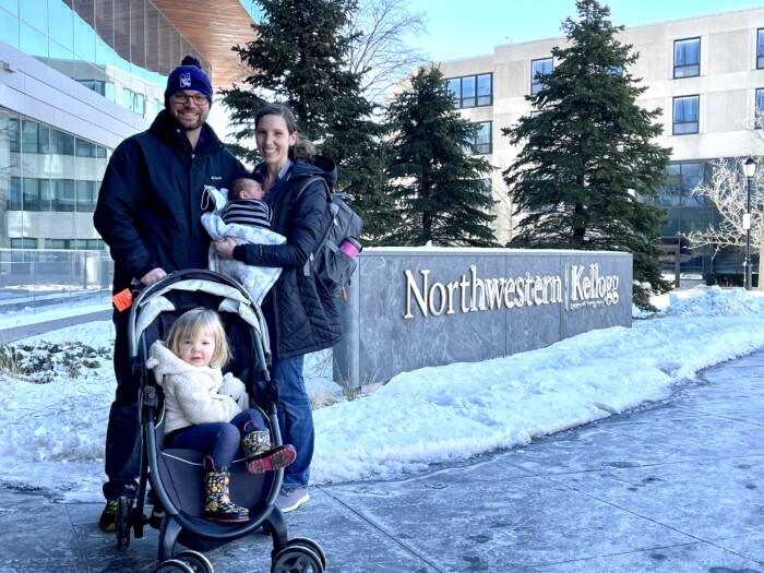 A dad, mom and two small children in front of the Northwestern sign. 