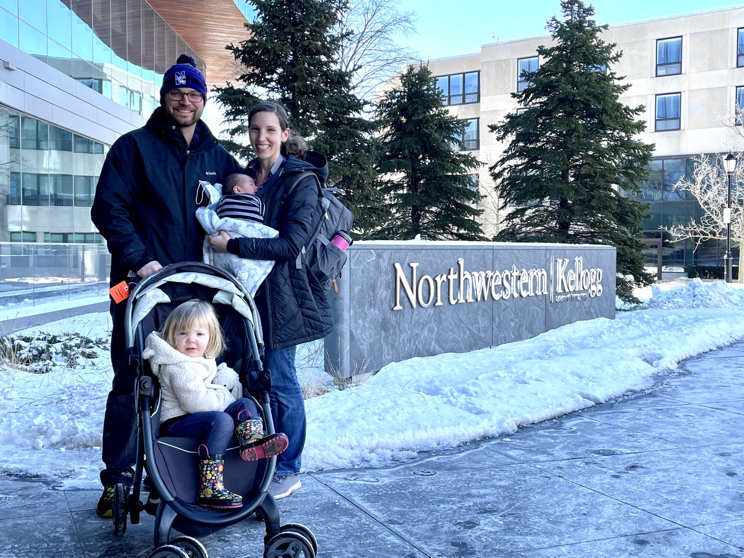 A dad, mom and two small children in front of the Northwestern sign.