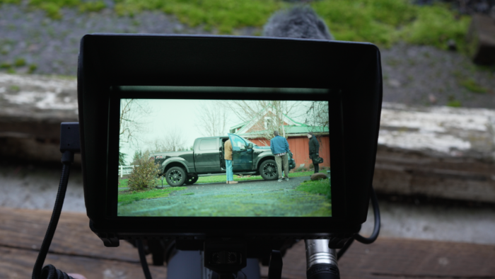 A video camera viewing screen looking on a black pickup truck. 