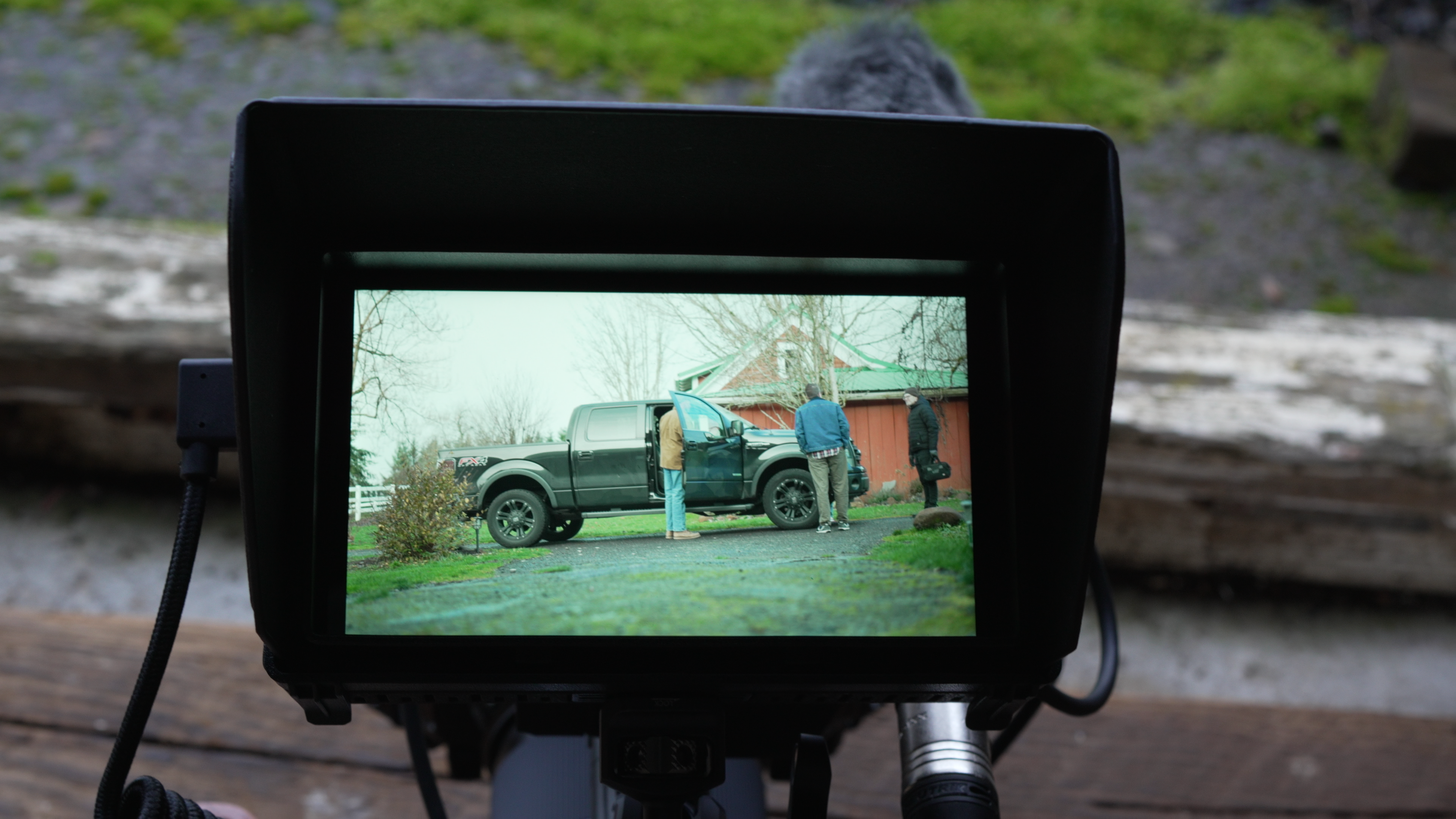 A video camera viewing screen looking on a black pickup truck.