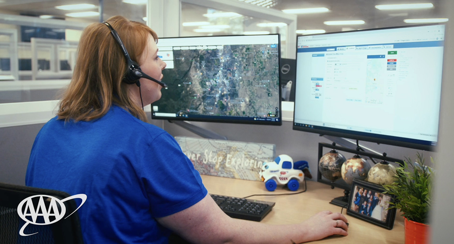 A call center employee of AAA at her desk monitoring incoming calls for assistance.