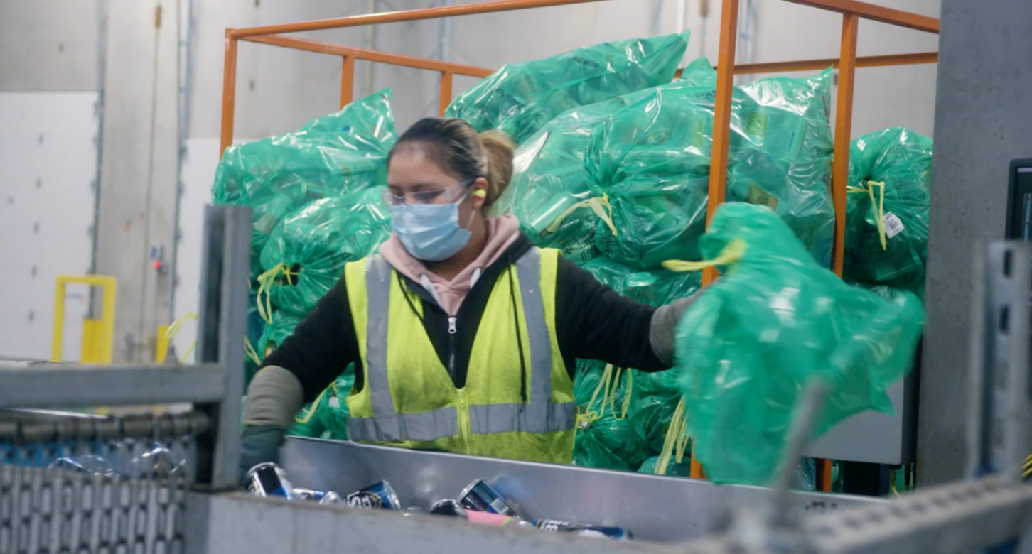 A screenshot depicting a woman working in a container sorting factory, from OBRC's "Small Deposit, Big return" video.