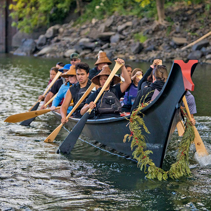 Members of the Confederated Tribes of Grand Ronde paddle a traditional canoe on the Willamette river, Oregon.