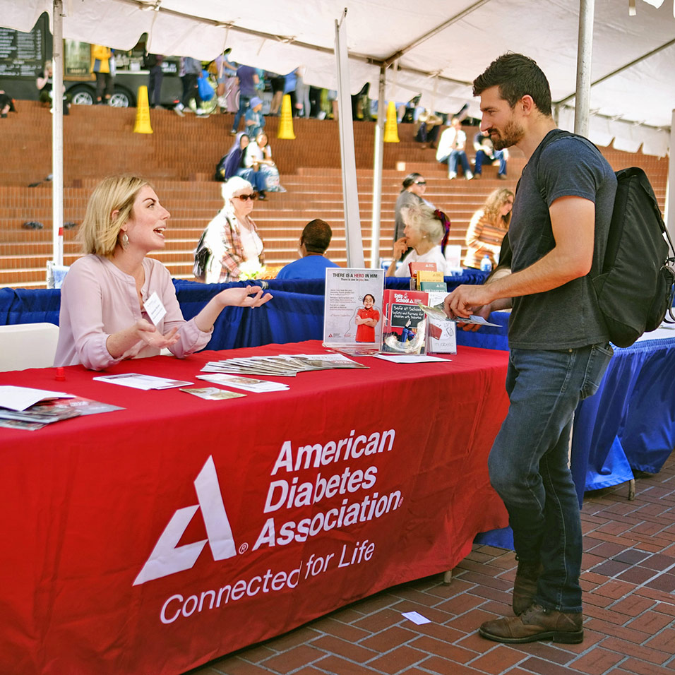 A nonprofit rep at a booth talks with a potential volunteer at the Standard Volunteer Expo in Portland's Pioneer Square.