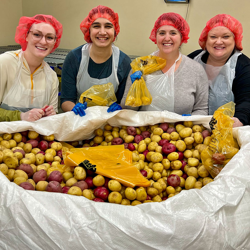 A group of Gard employees pack potatoes during a day-of-service at the Oregon Food bank.